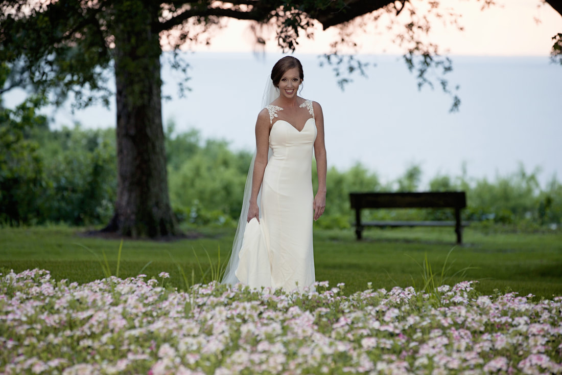 Bride standing in a field of wildflowers by the bay at dusk