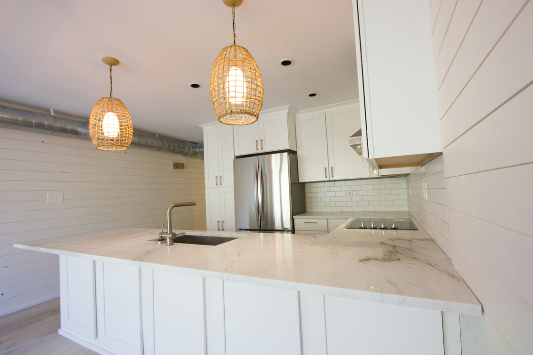 Bright white condo kitchen with marble counters and woven pendant lights