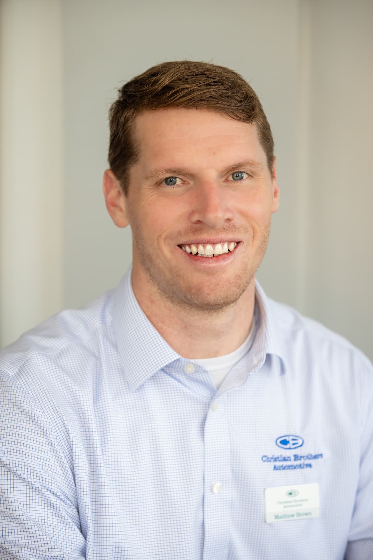 Automotive shop owner headshot in a light blue shirt