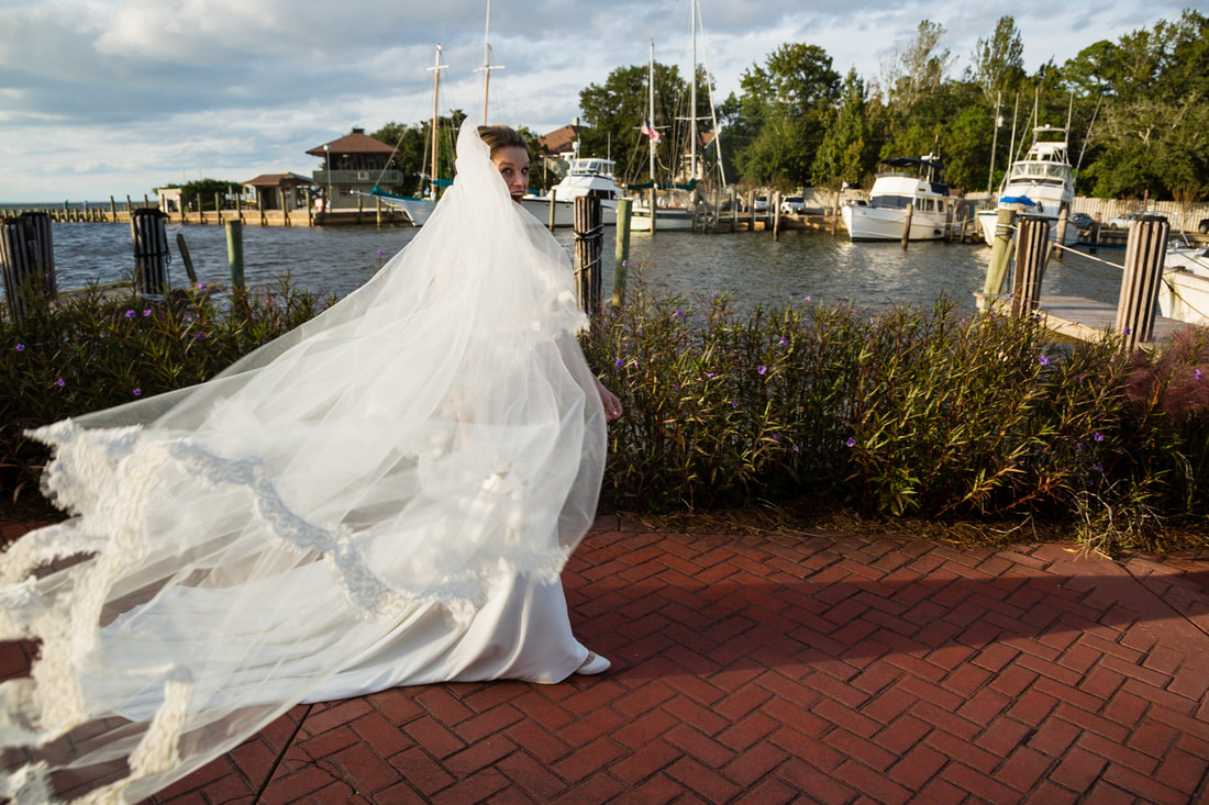Bride in a long veil walking along the waterfront