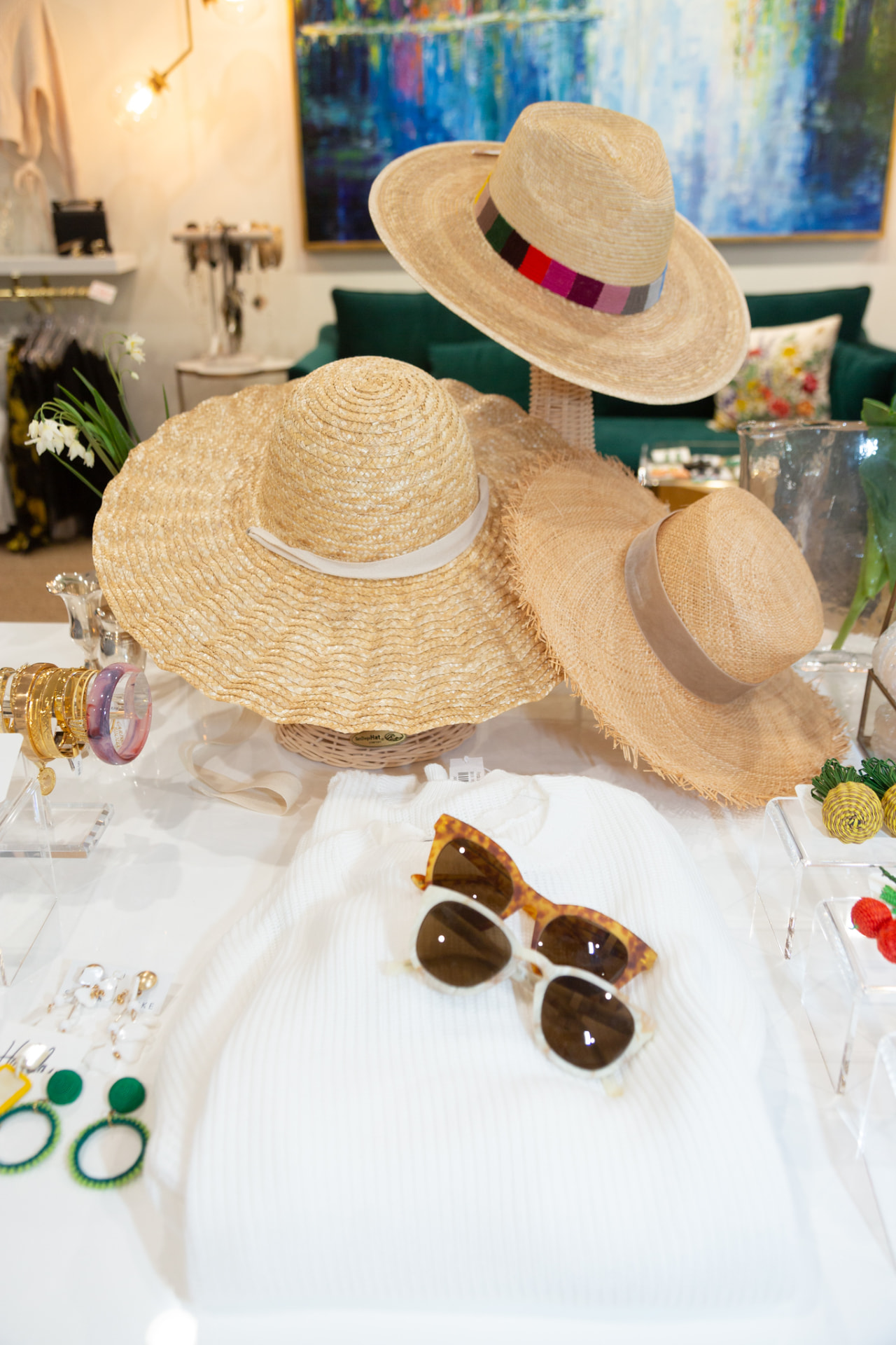Straw hats, sunglasses and jewelry styled on a boutique table