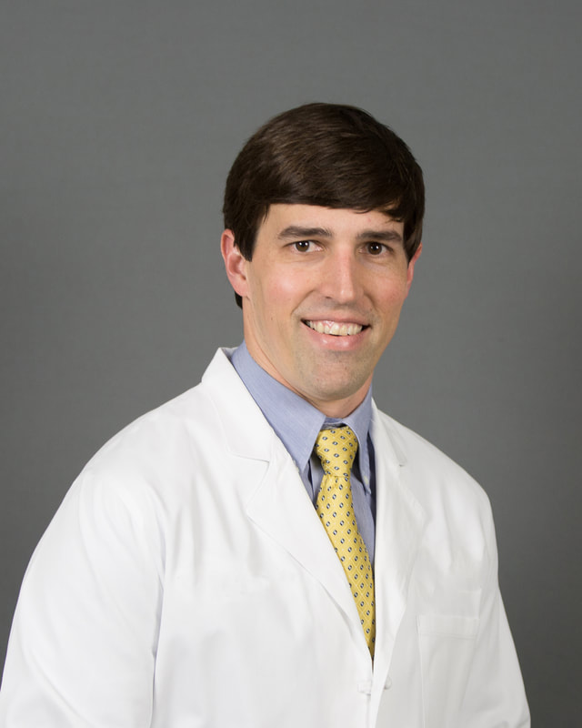 Physician in white coat, corporate headshot on gray backdrop