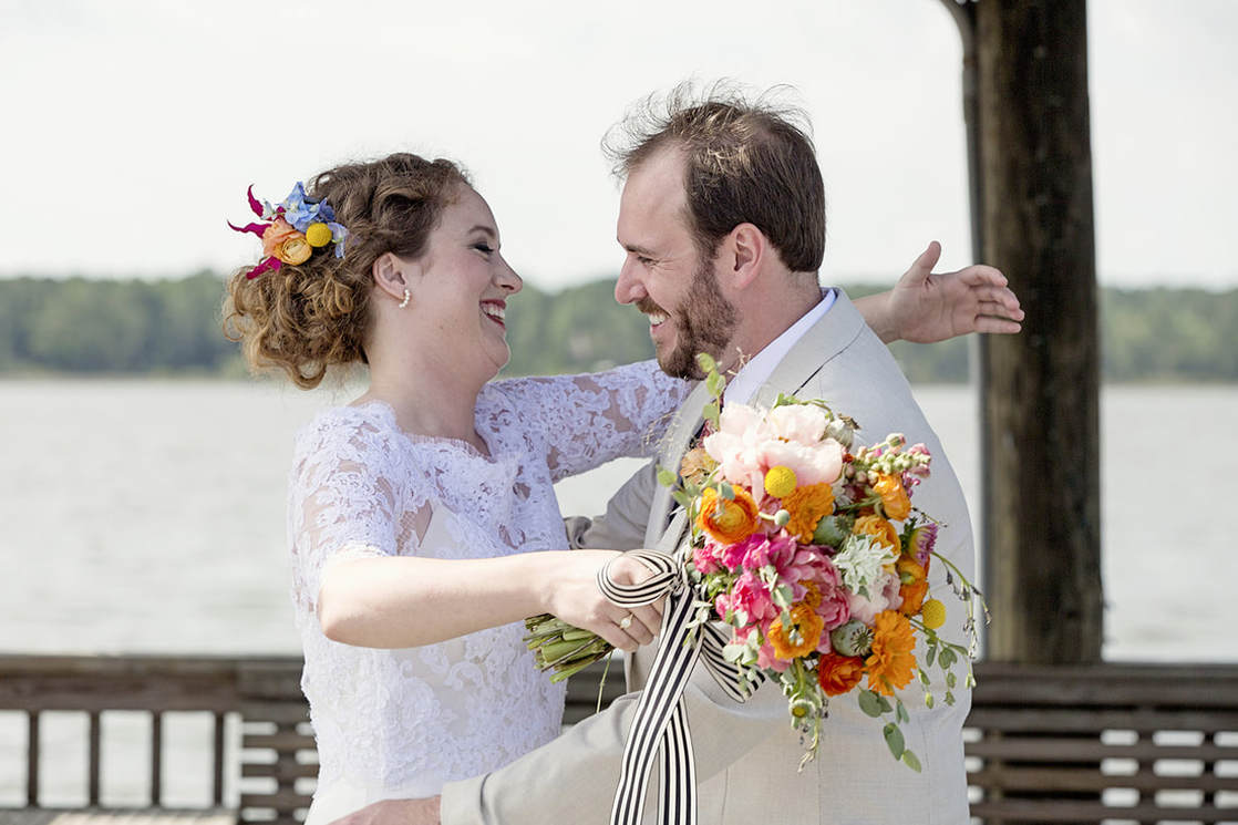 Bride and groom laughing together on a waterfront pier