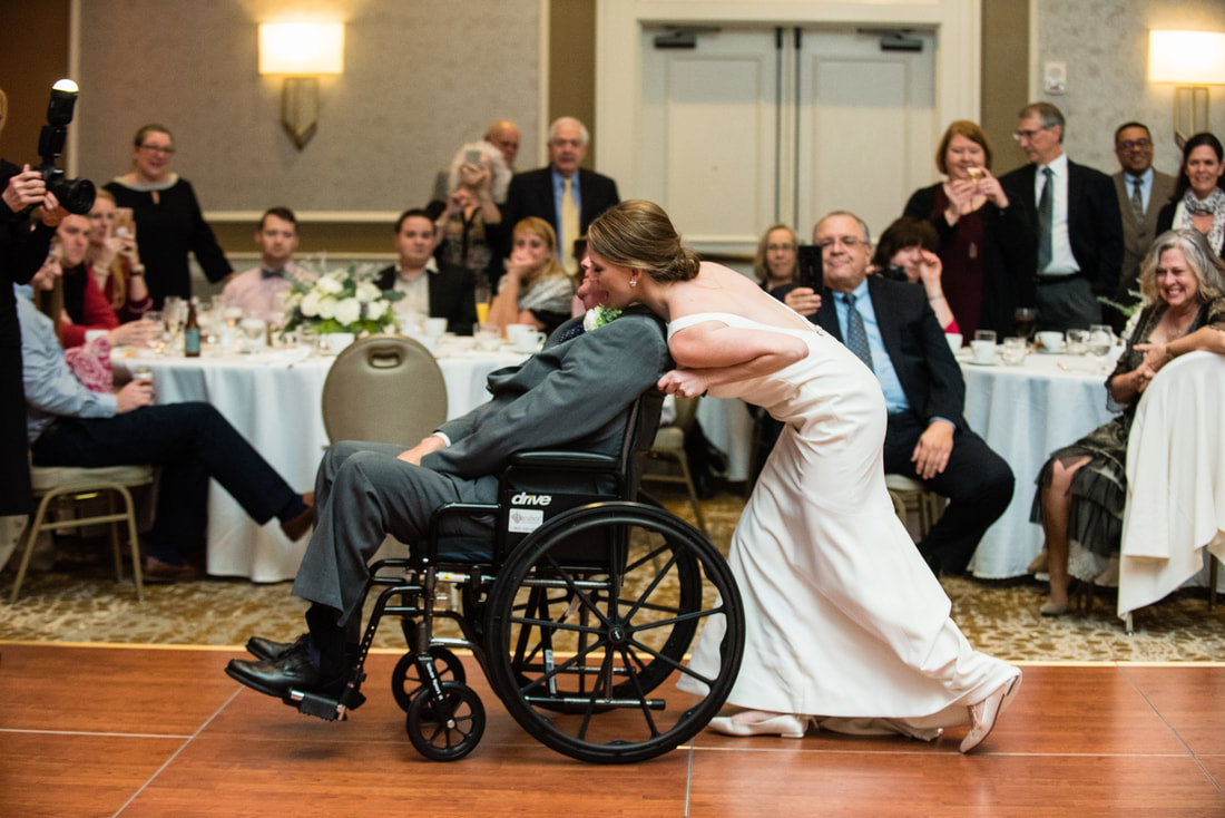 Bride dancing with a guest in a wheelchair at the reception