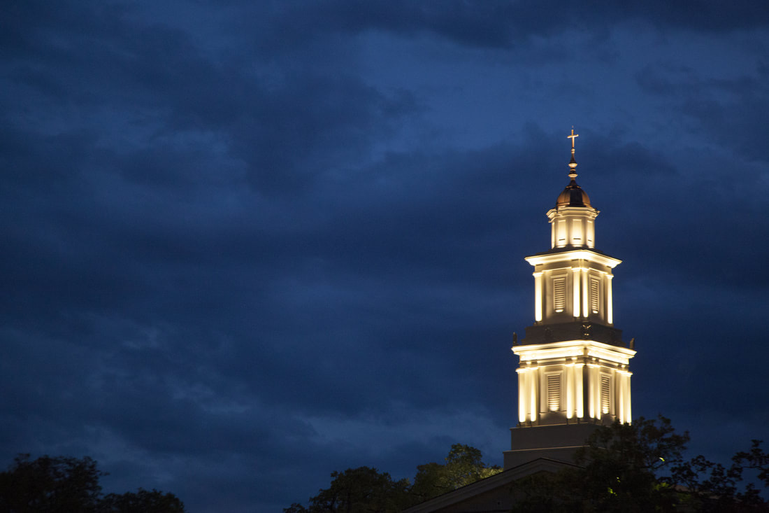 Illuminated church steeple against a deep blue evening sky