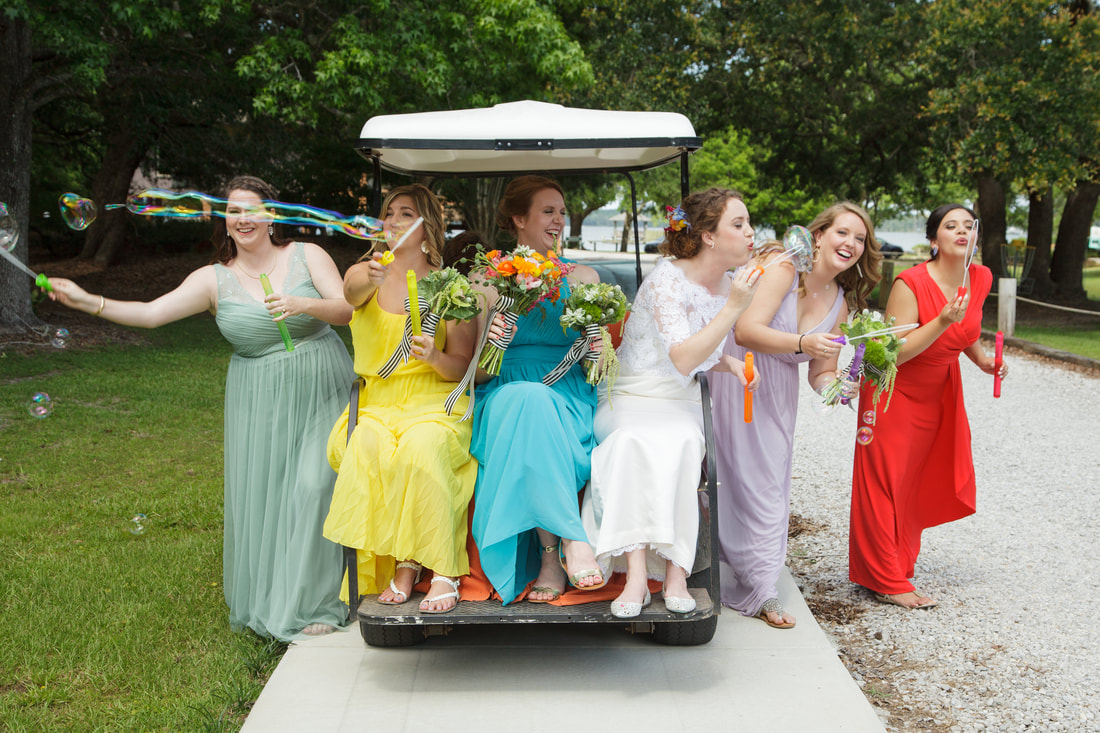 Bridesmaids blowing bubbles from a golf cart