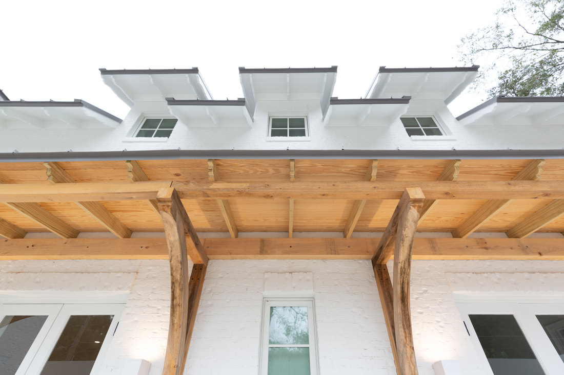 Timber porch beams and dormer windows on a white brick home