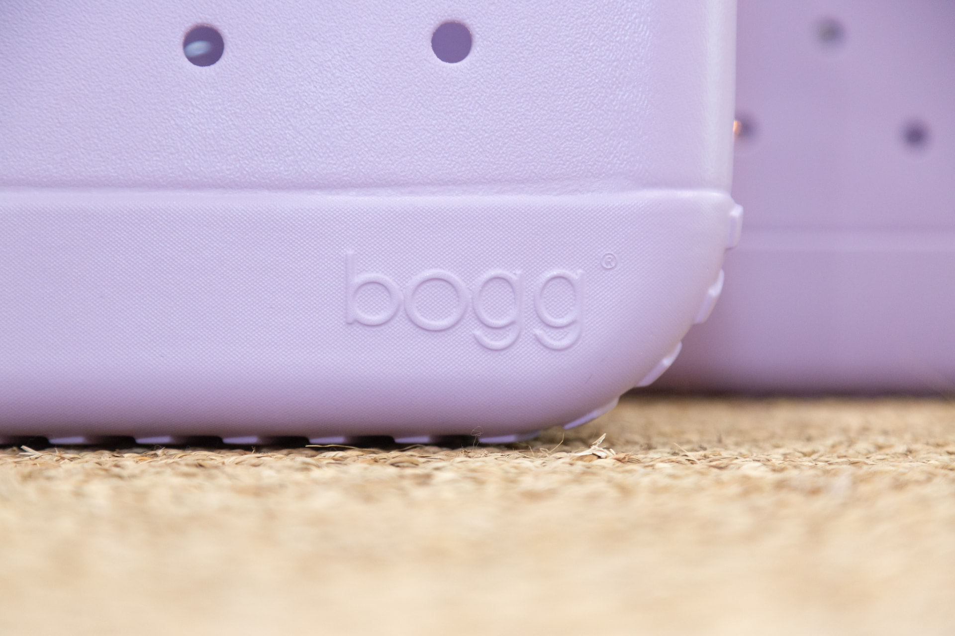 Detail of a lavender Bogg bag on a woven jute rug