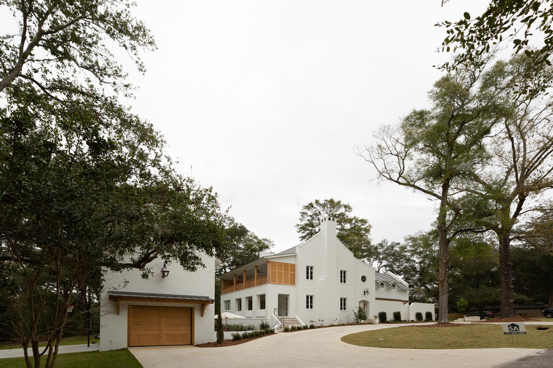 White brick residence and detached garage under live oaks
