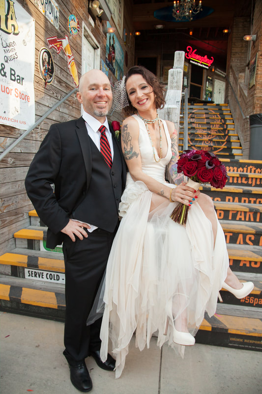 Couple posing on painted stairs outside a bar
