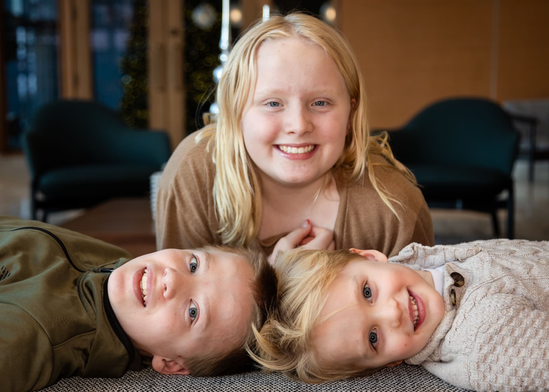 Three siblings laughing for a Christmas card portrait