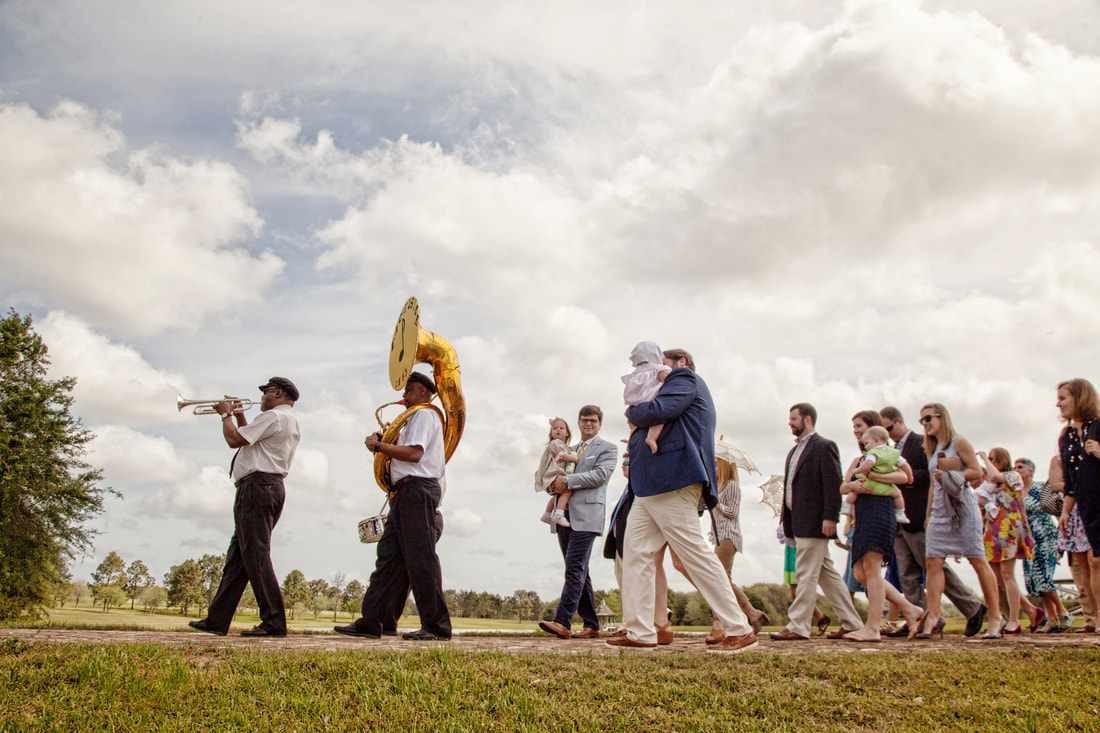 Second line brass band leading guests across the lawn