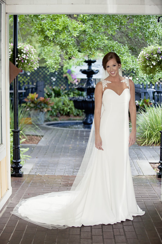 Bride with a long train beside a garden fountain