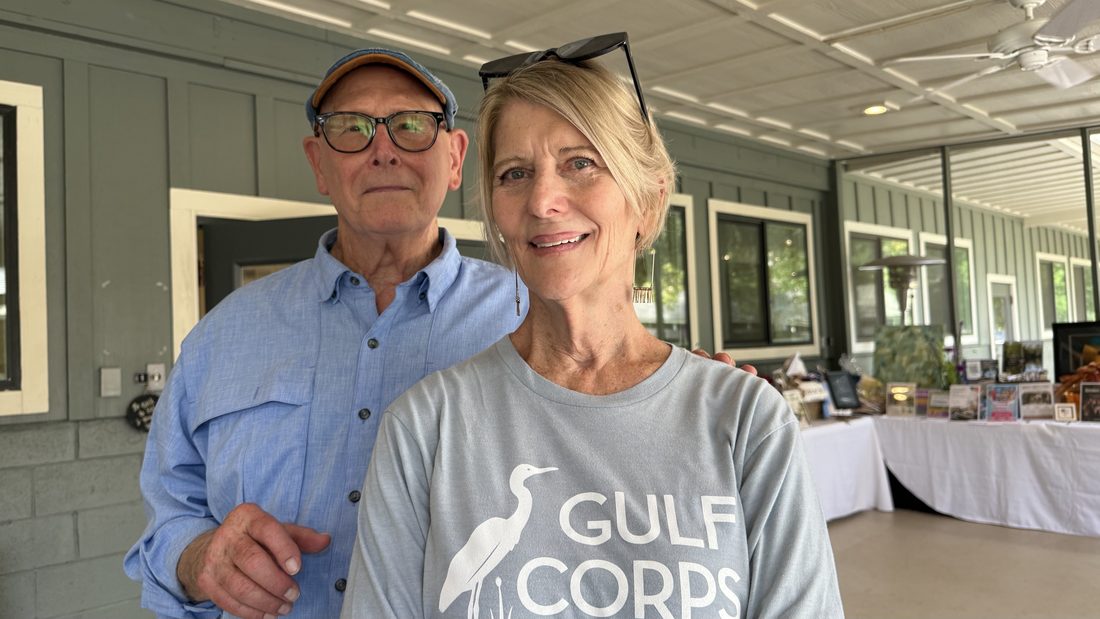 Cindy with a friend under the tent in Gulf Coast shirts