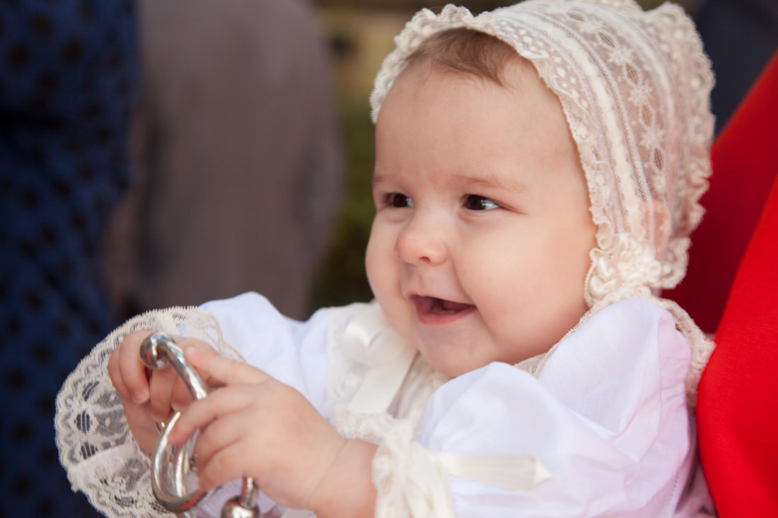 Baby in a lace christening bonnet smiling after a baptism