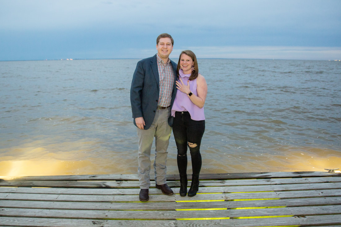 Newly engaged couple on a pier at dusk