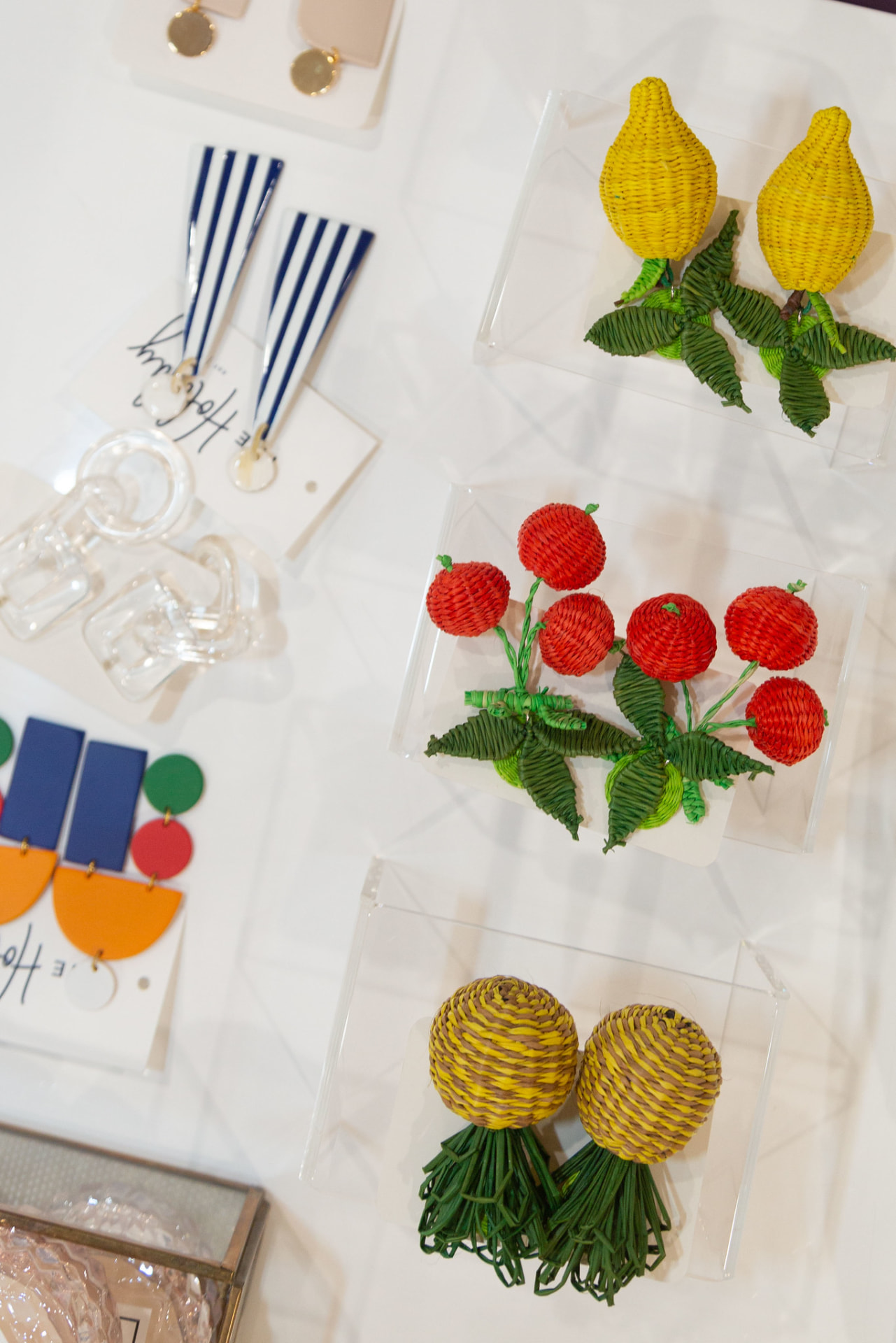 Woven fruit statement earrings displayed on acrylic risers