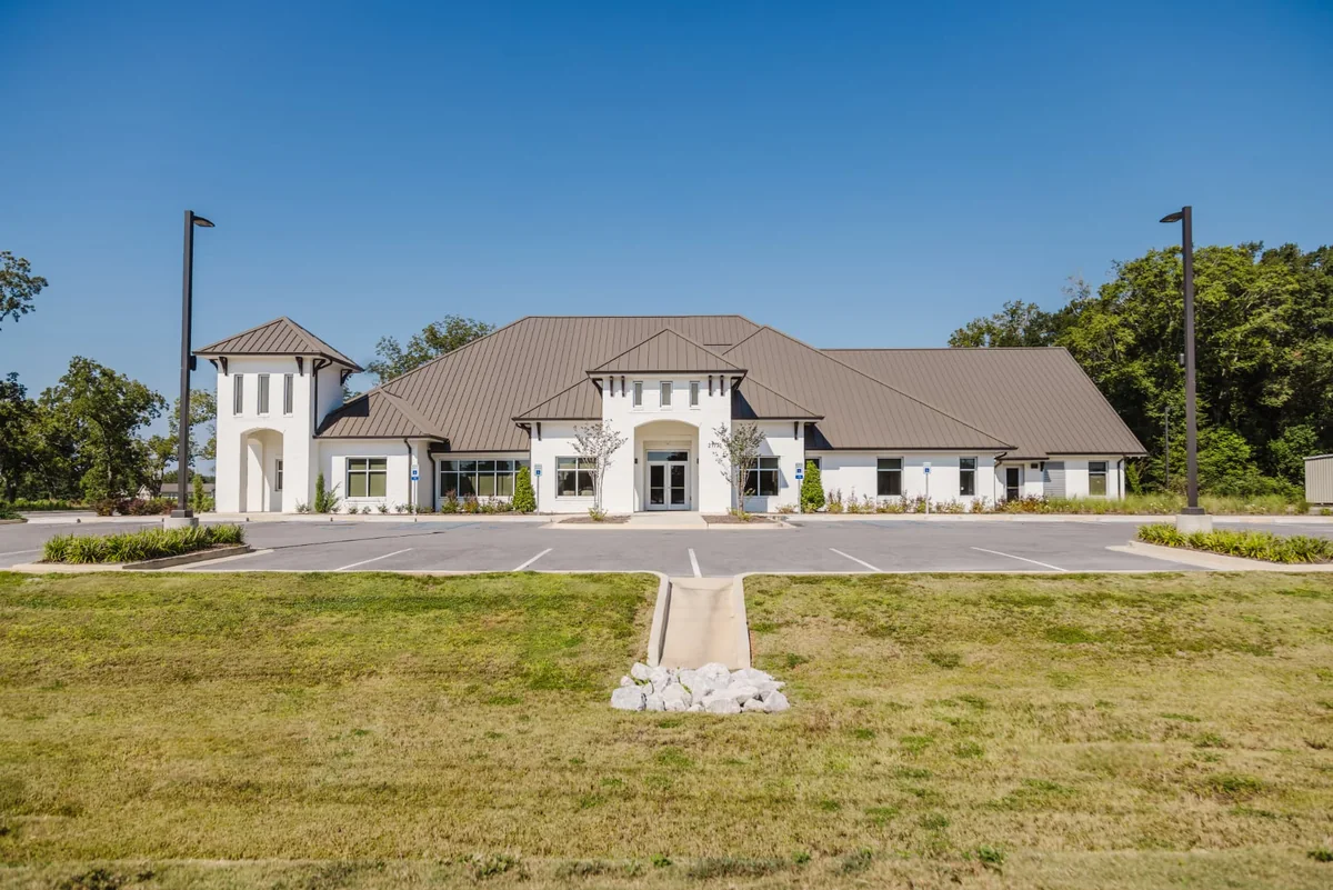 White dental office building with a metal roof, parking area, and lawn in Robertsdale