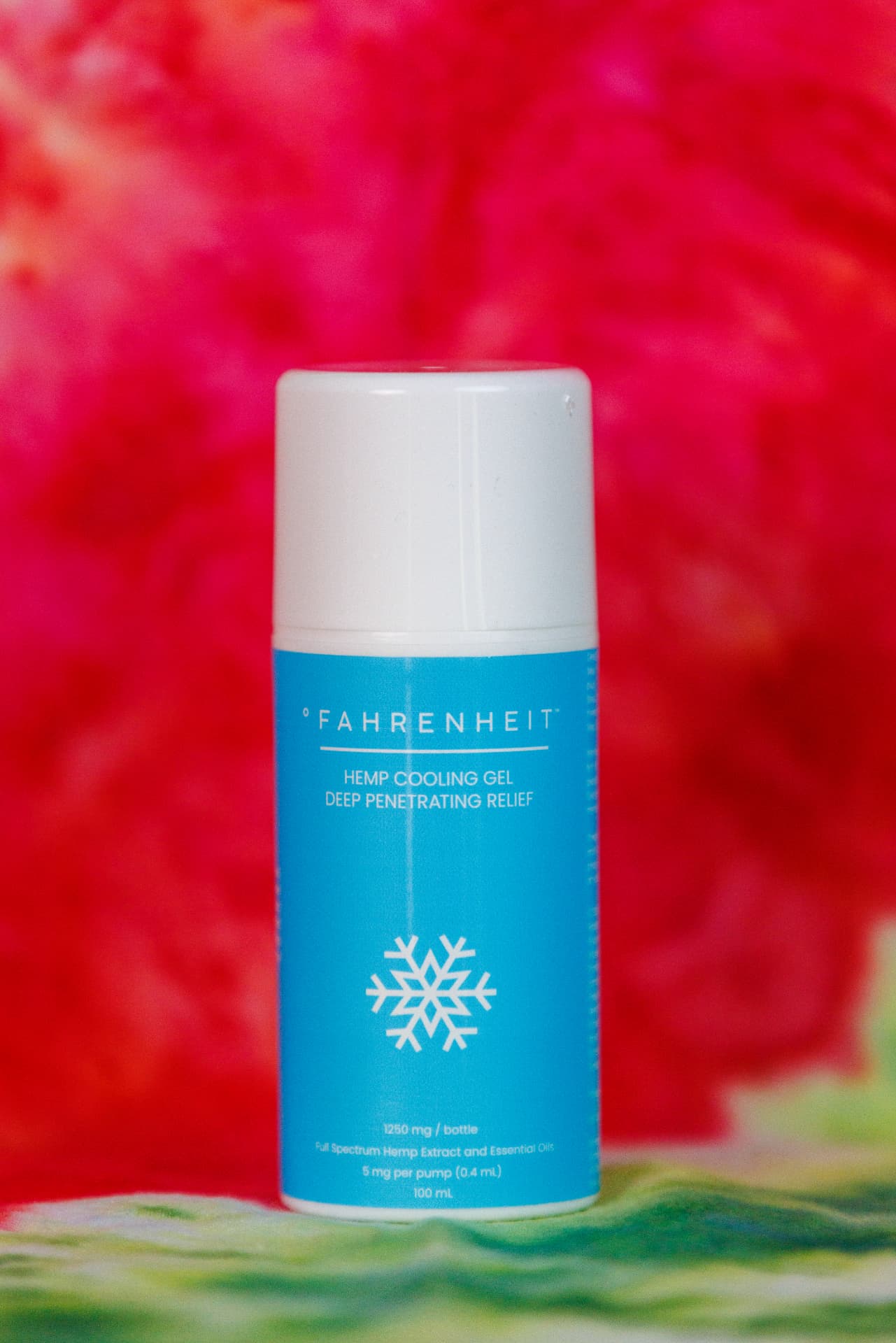 Fahrenheit hemp cooling gel bottle in front of red blooms