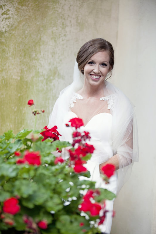 Bride smiling behind red geraniums