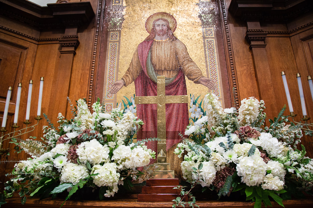 Church altar with white floral arrangements and a gold cross