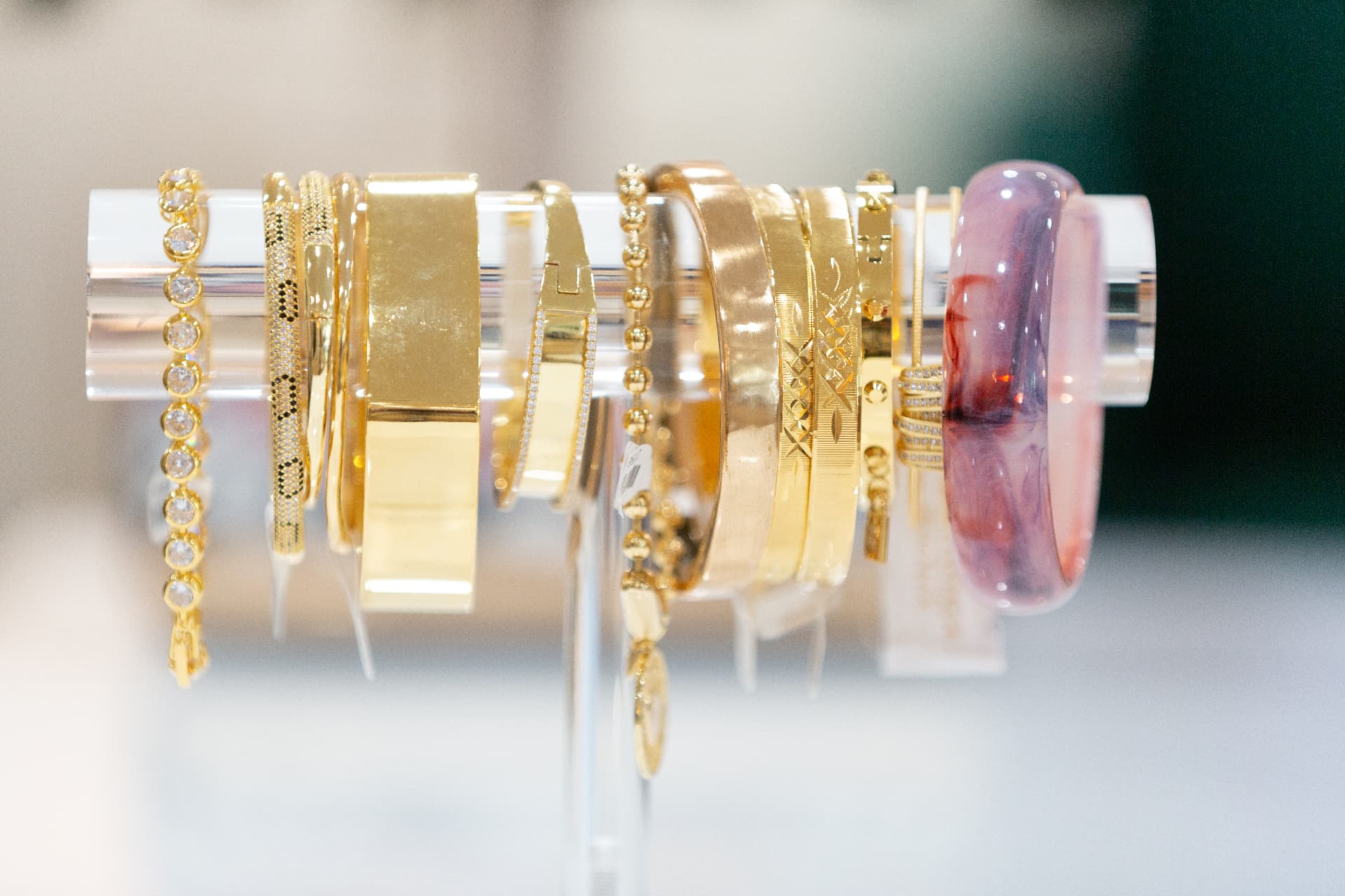 Gold bangles and bracelets styled on a boutique display bar