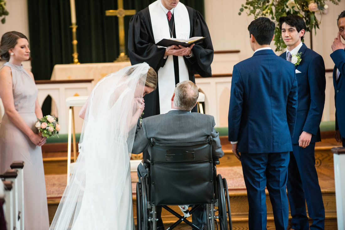 Bride leaning to kiss her father in the aisle during the ceremony