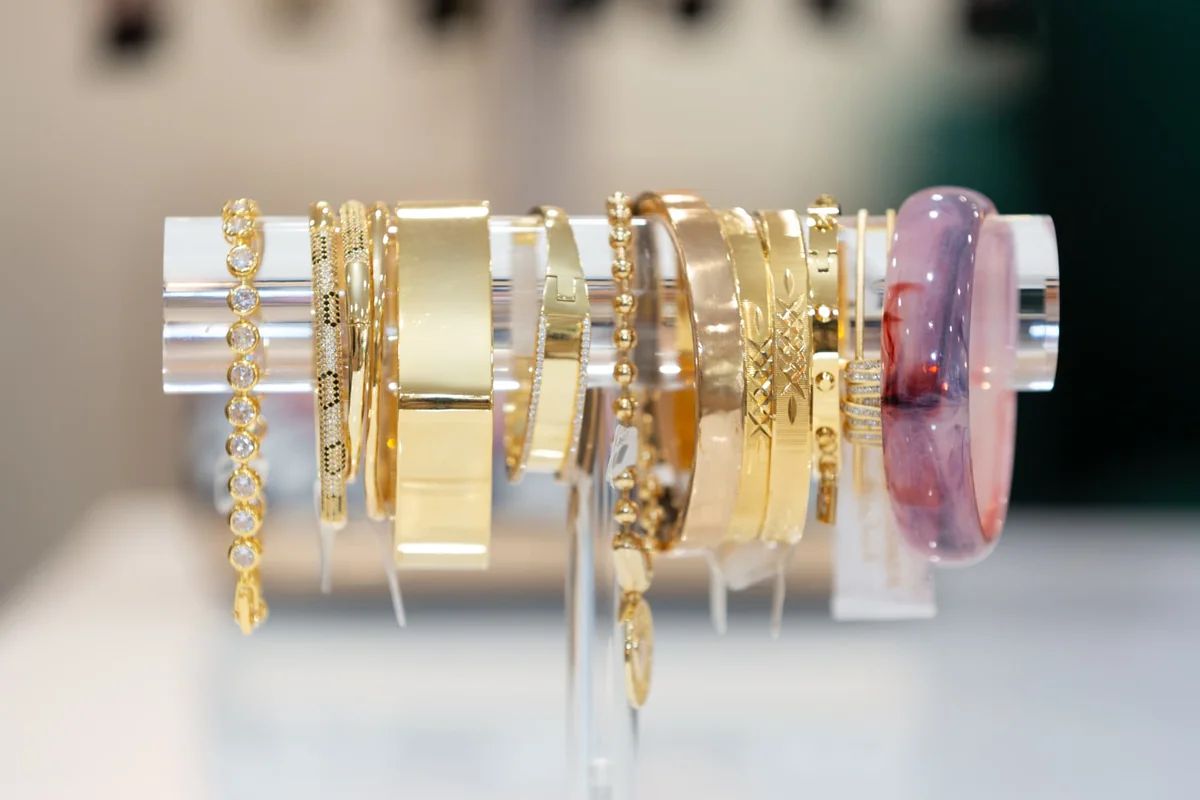 Gold and pink bracelets displayed on a clear jewelry stand at The Holiday