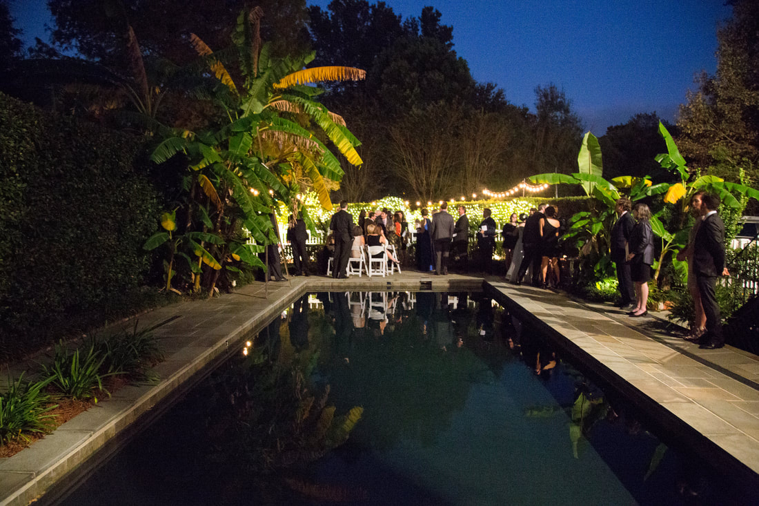 Evening reception beside a lit pool and banana palms