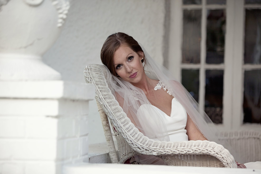 Bride resting in a wicker chair on a white porch